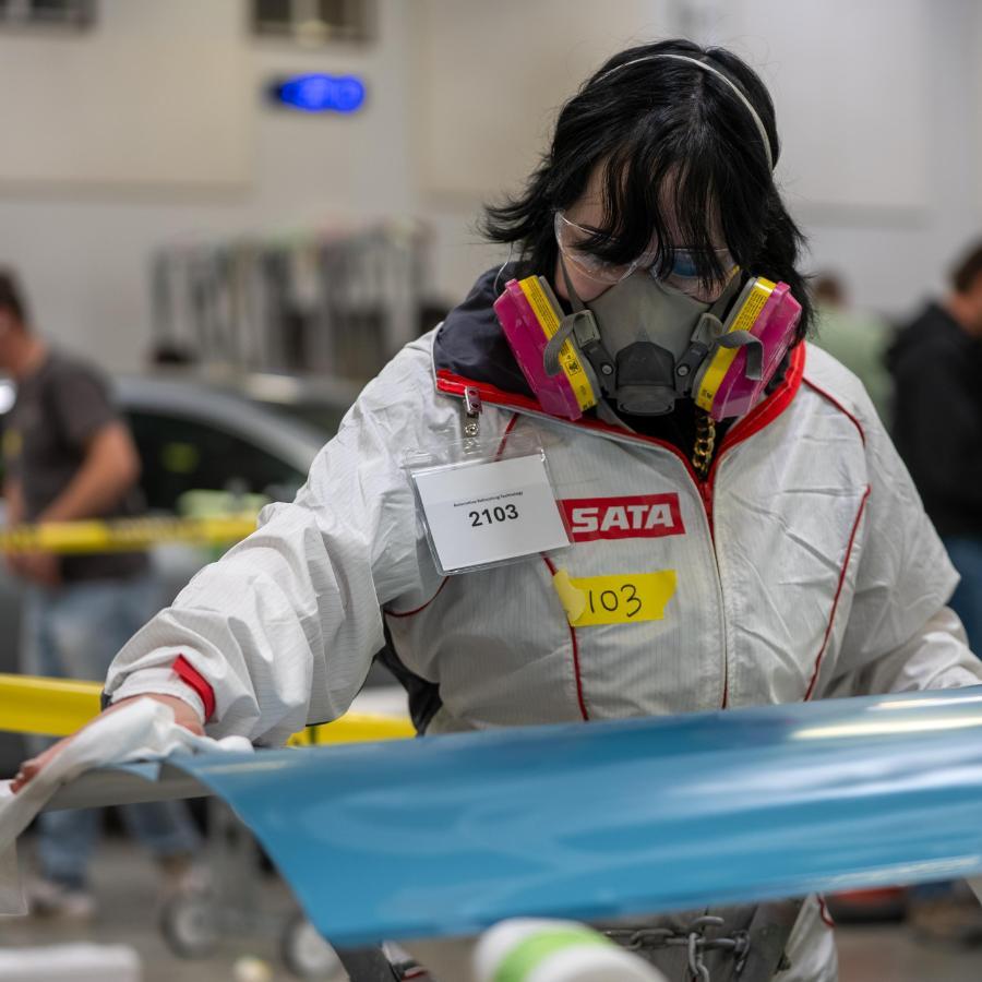 female student working on paint on car