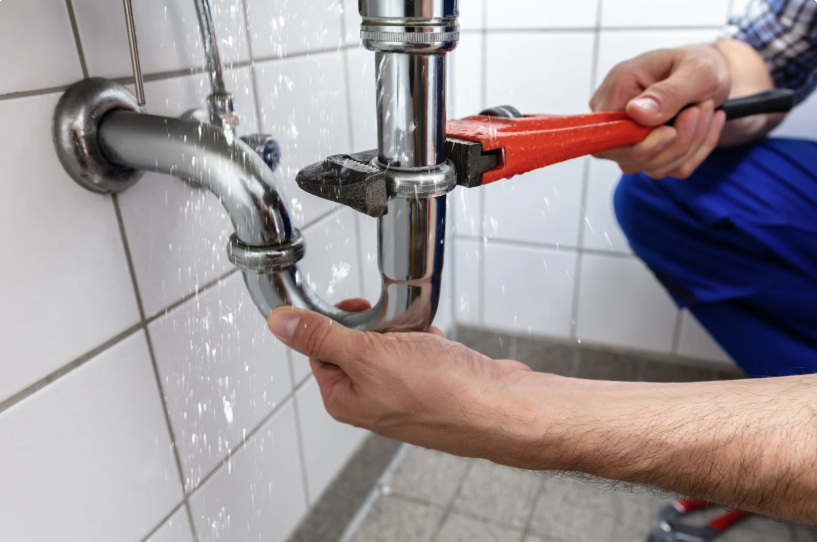 Student using a crescent wrench on a sink pipe